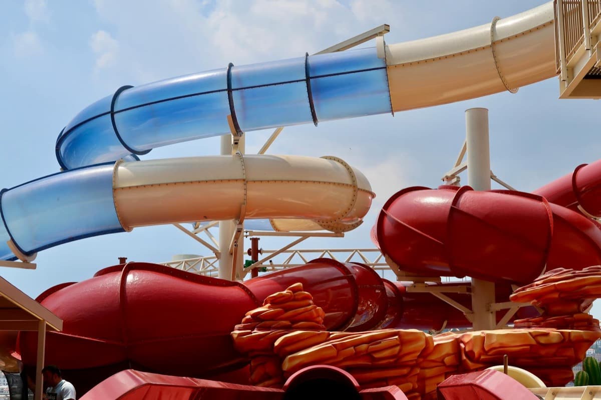 Blue and red water park slides twisting against a clear sky (16:9)