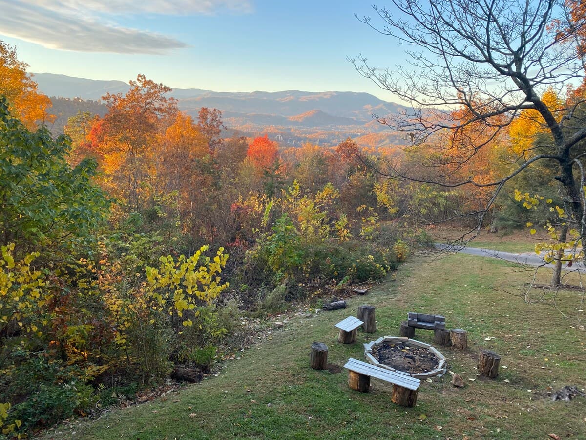 Fire pit with log bench overlooking autumn valley views and Smoky Mountain ridges at sunset