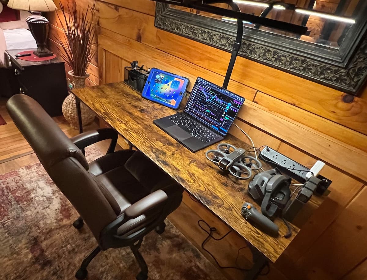 Remote workspace desk with laptop, iPad, office chair, and desk lamp