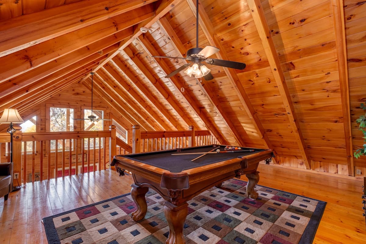 Open loft overlooking living room below with pool table and vaulted pine ceiling