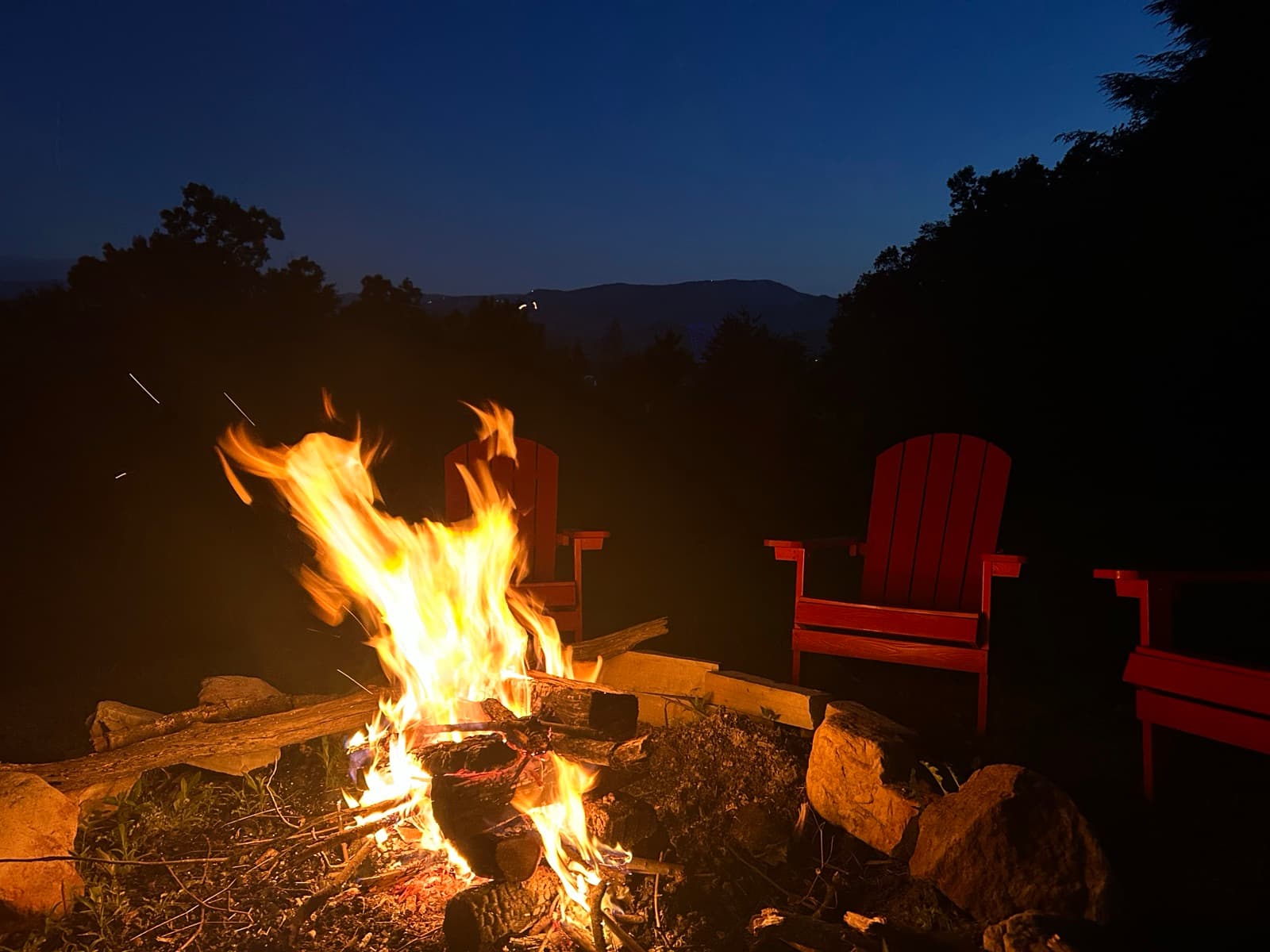 Firepit at dusk with red Adirondack chairs and layered Smoky Mountain views