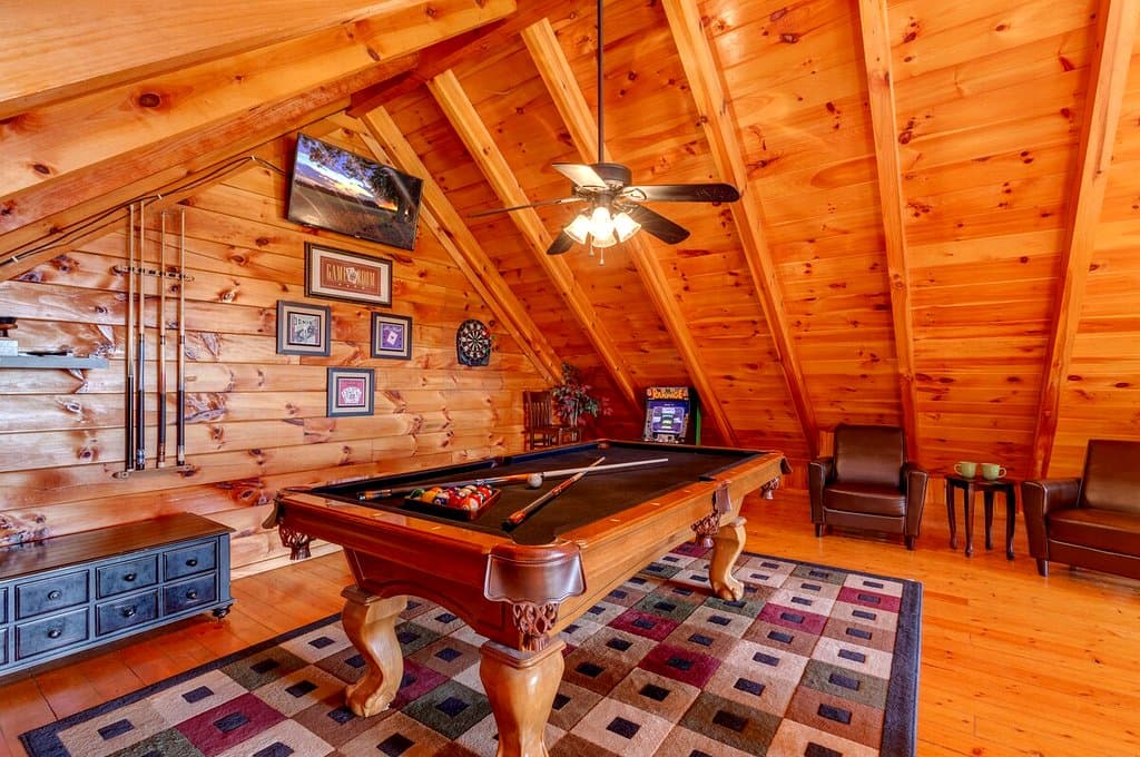 Loft game room with a pool table, arcade cabinet and dartboard