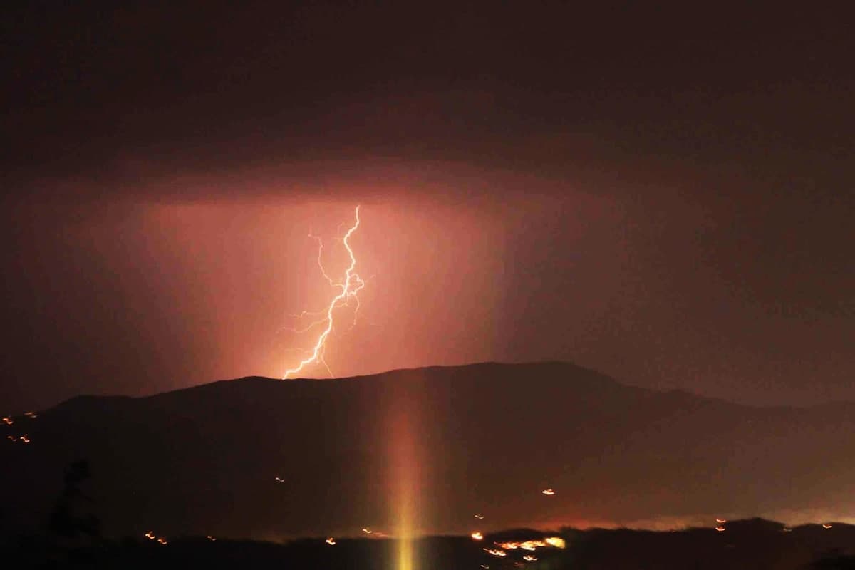 Lightning bolt striking over the Smoky Mountains viewed from the cabin at night with orange-pink sky
