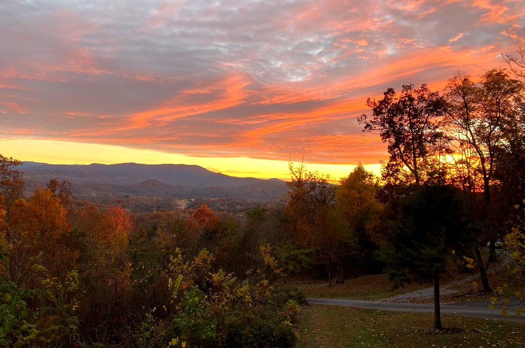 Actual photo from Thistle Britches: Orange sunset above the cabin yard and wooded mountains